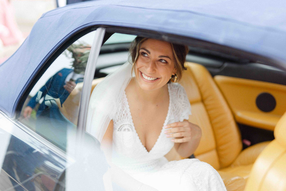 Mariée souriante assise dans une voiture de mariage – par Julien Stevens Photography