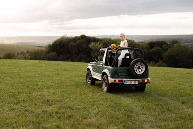 Mariée debout à l’arrière d’une Jeep verte au milieu d’un champ – par Julien Stevens Photography