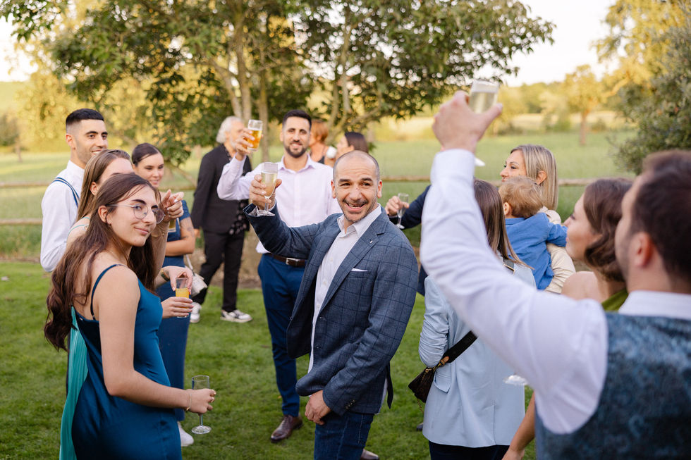 Ambiance festive pendant un toast au jardin, les invités et le marié trinquent avec le sourire – par Julien Stevens Photography