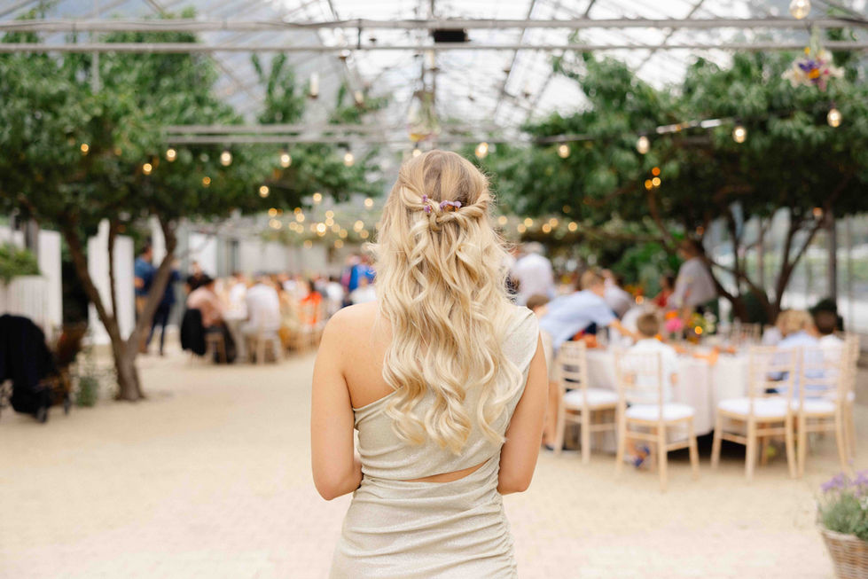 Vue de dos d’une invitée blonde marchant vers une réception de mariage en plein air – par Julien Stevens Photography
