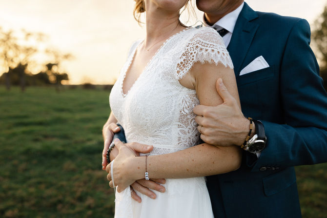 Tendre étreinte des mariés, leurs mains entrelacées sur la taille de la mariée, capturée avec délicatesse – par Julien Stevens Photography