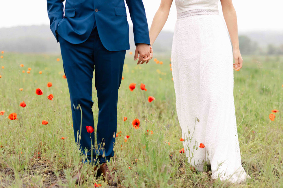Couple marié marchant main dans la main dans un champ fleuri de coquelicots – par Julien Stevens Photography