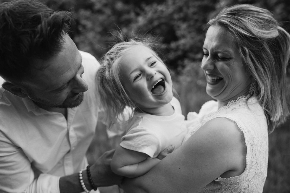 Laughter shared between a little girl and her parents in soft black and white light – by Julien Stevens Photography