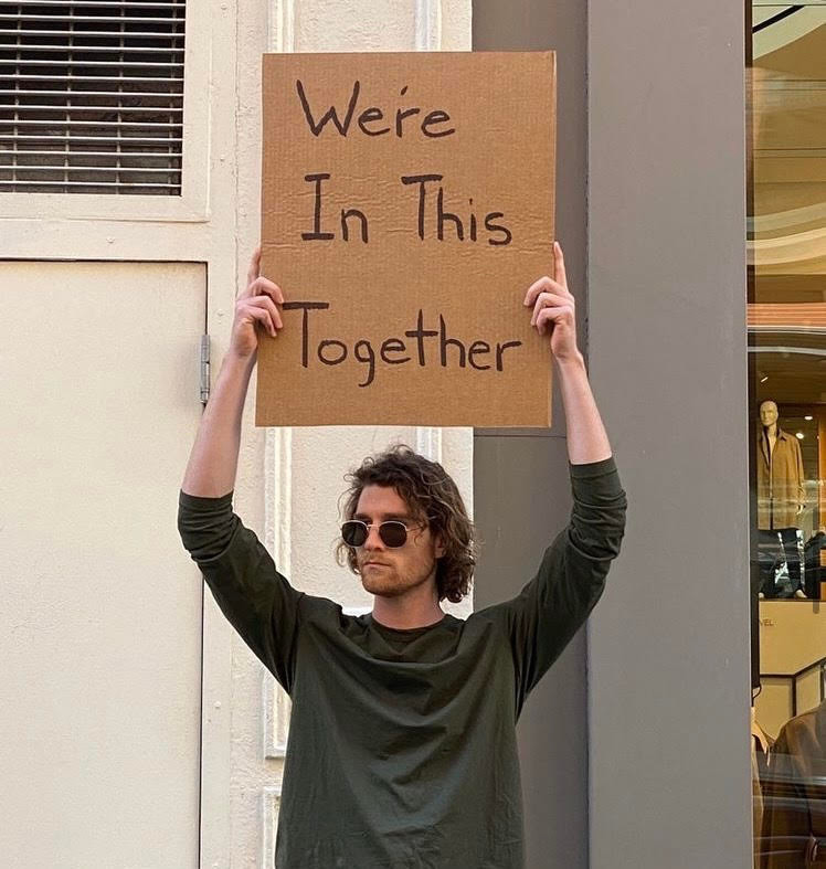 Dude with a sign saying "we're in this together"