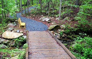 Pedestrian bridge with slate lined trail by Tailored Trails