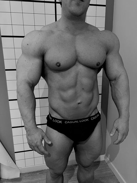 Un uomo muscoloso in biancheria intima posa davanti a una griglia di rilevazione posturale nello studio del Dott. Nicola Giacintucci, osteopata a Milano, evidenziando la sua struttura muscolare sviluppata.