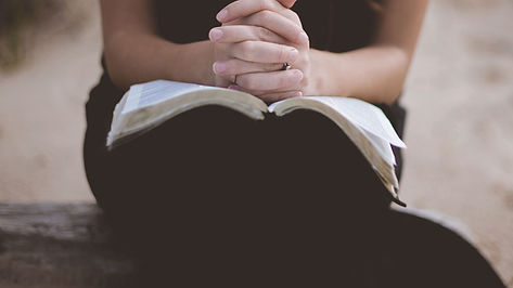 Woman with Bible open praying