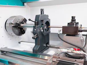 Large industrial CNC lathe machine with metal workpiece in chuck.