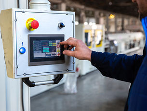An operator using a digital HMI panel to monitor and adjust real-time process control parameters in a factory.