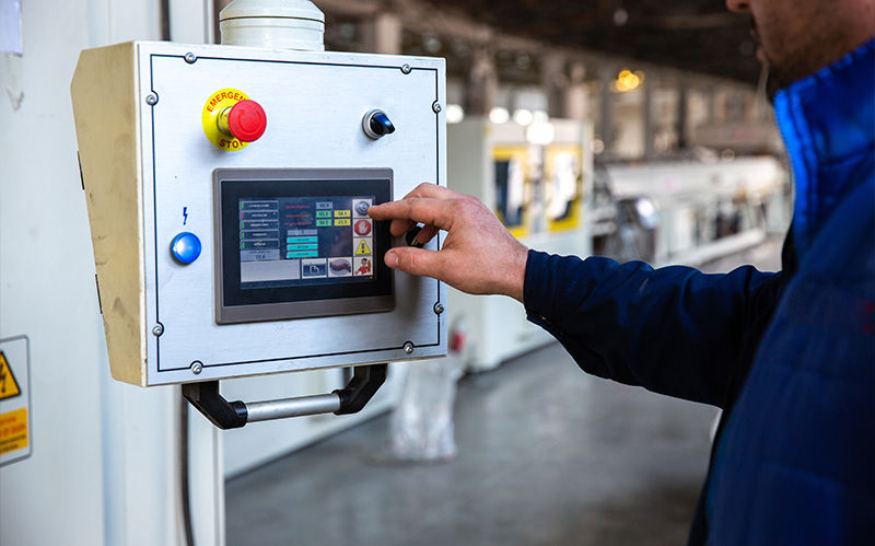 An operator using a digital HMI panel to monitor and adjust real-time process control parameters in a factory.