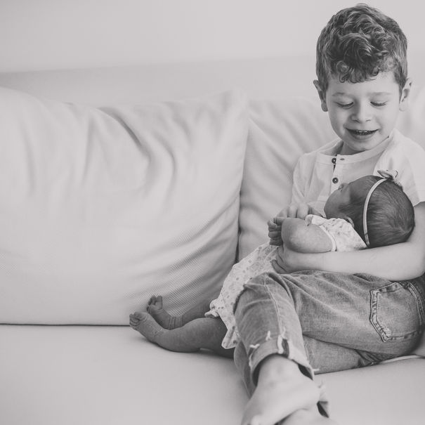 big brother holding newborn sister 
