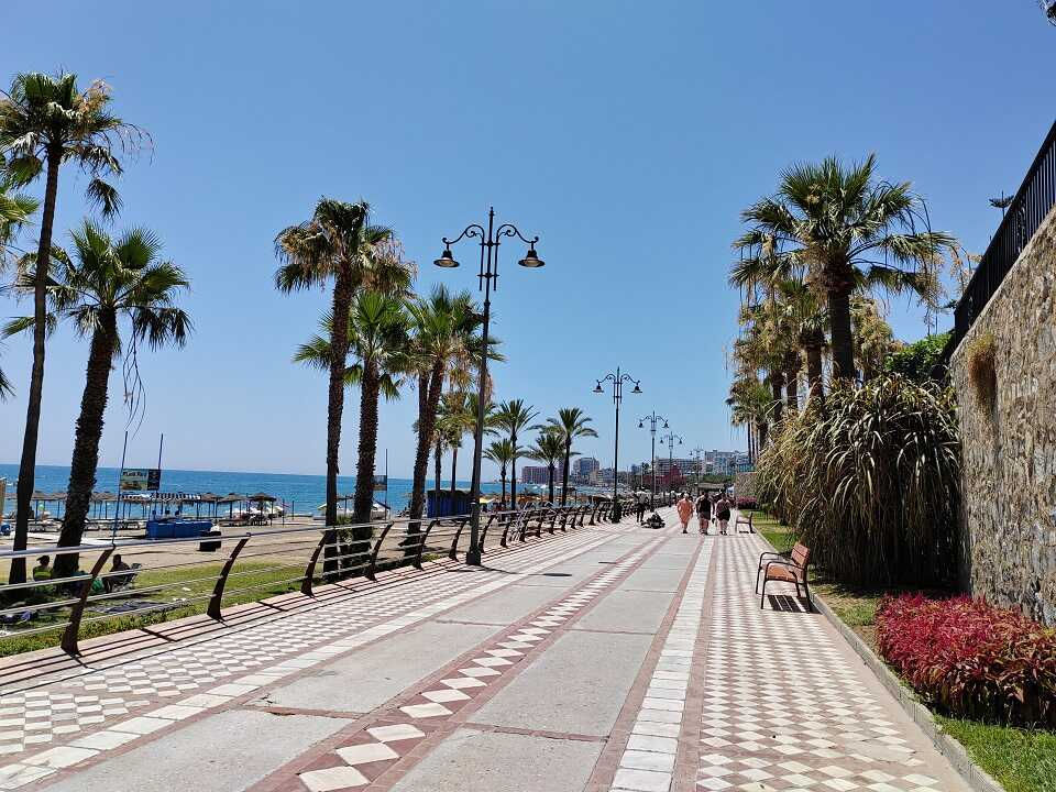 Benalmádena tengerpart sétány pálmafákkal és piros virággokkal, kék ég