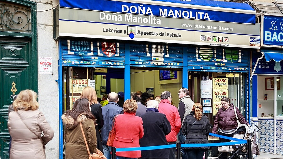 Emberek sorban állnak a Doña Manolita lottózó előtt Madridban. A háttérben épületek, a hangulat feszült, várakozó.
