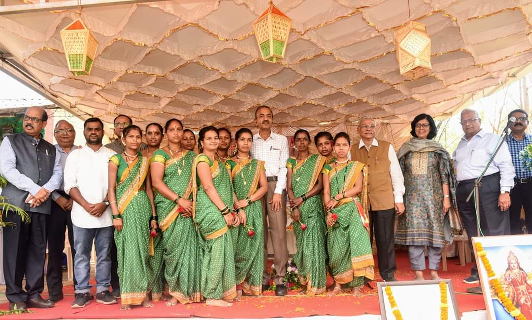 Dignitaries and tribal women artisans in green sarees under festive pandal