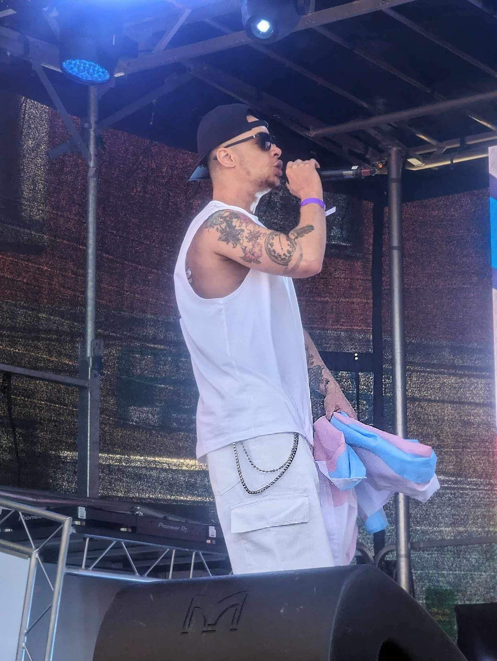 Person performing on outdoor stage, wearing white outfit.