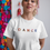 Thumbnail: woman wearing a white t shirt with the word Dance on the front in bright colours
