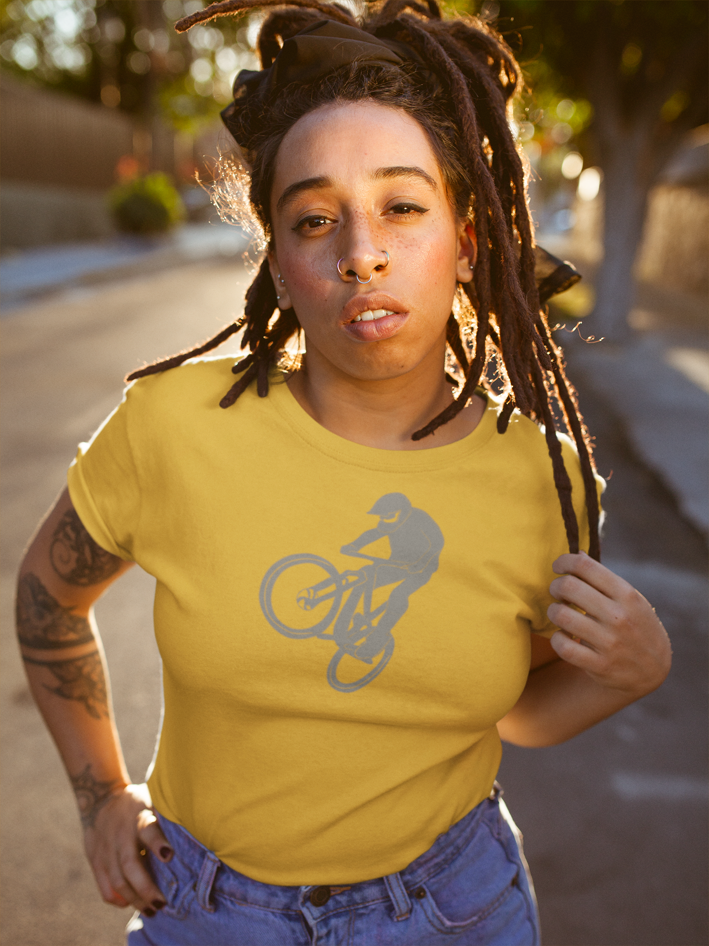 Black woman with dreds wearing a yellow t shirt with a silhouette design of a mountain biker on the front