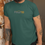 Thumbnail: Man with a beard and hat wearing a green t shirt featuring our four18 design and a line design of a hill