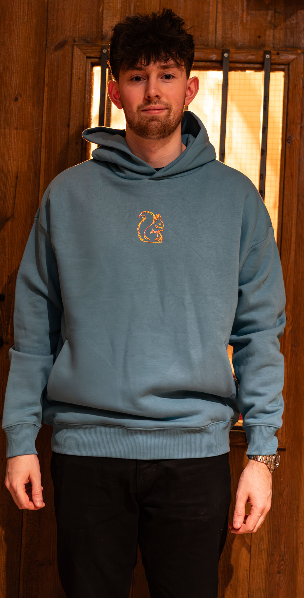 Man wearing a blue hoodie with a Fire themed black squirrel clothing design on the chest