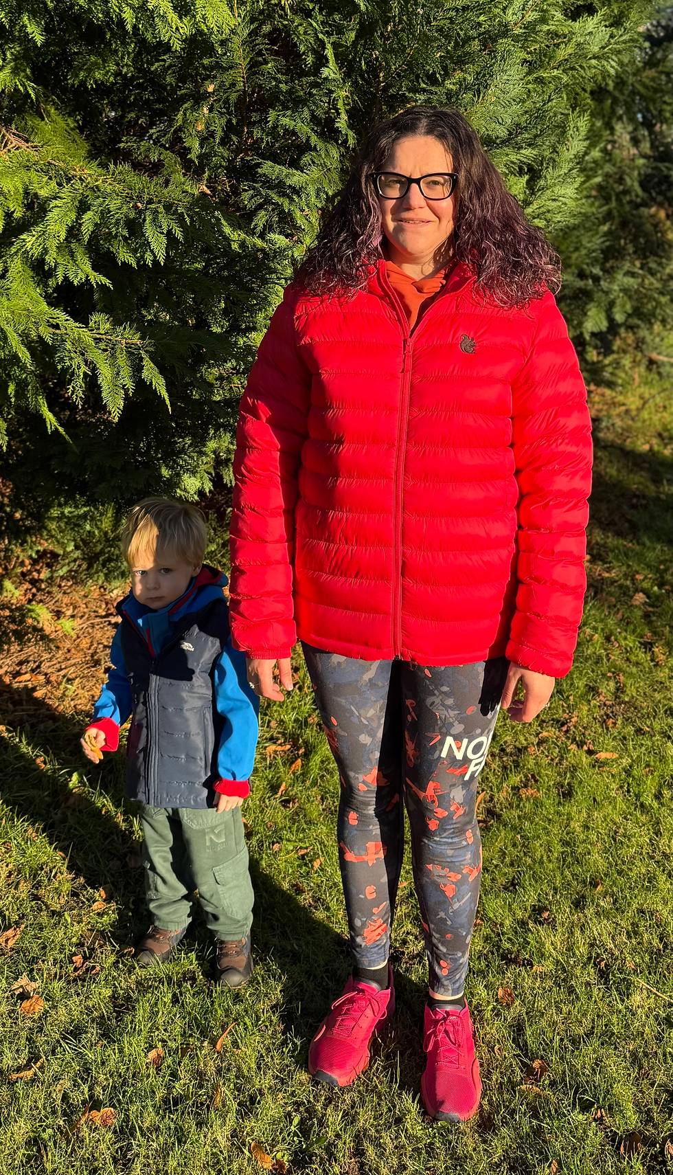 Thumbnail: Woman with glasses and long curly hair wearing a red black squirrel insulated jacket