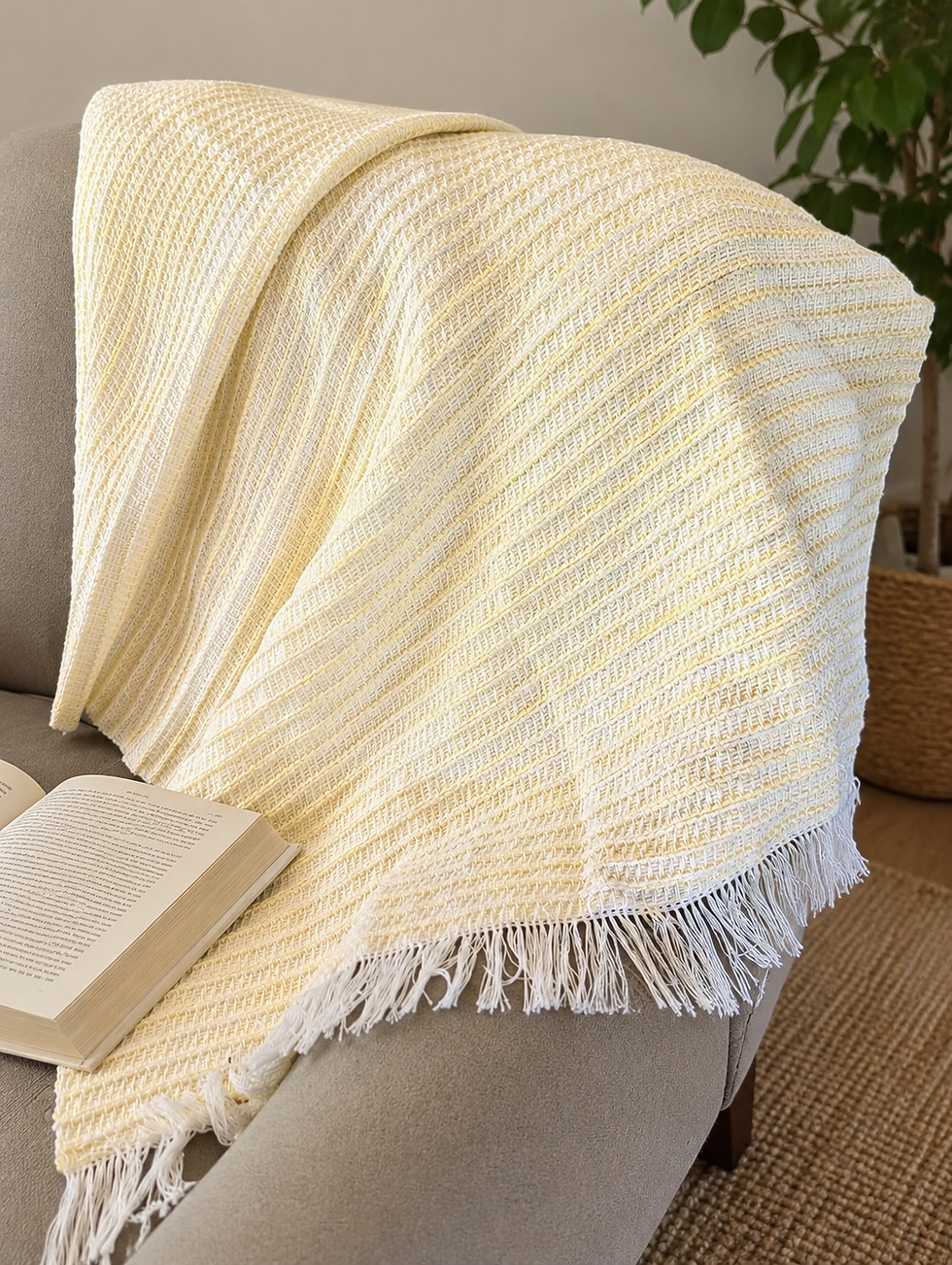 Soft yellow and white handwoven lap throw draped over an armchair, showing woven texture and white fringe