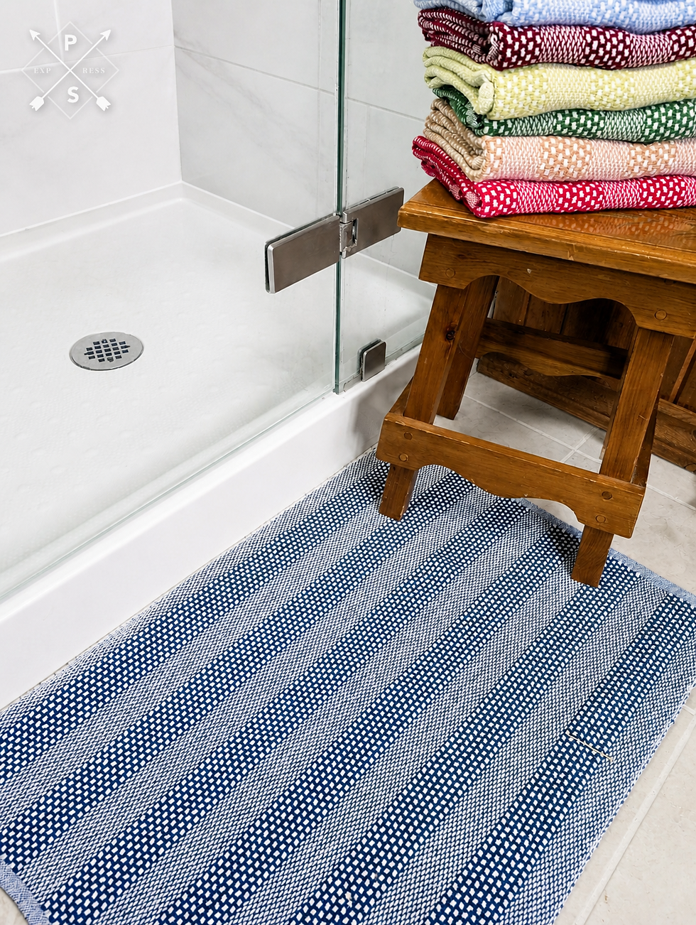 Blue and white handwoven cotton bath mat in front of a shower