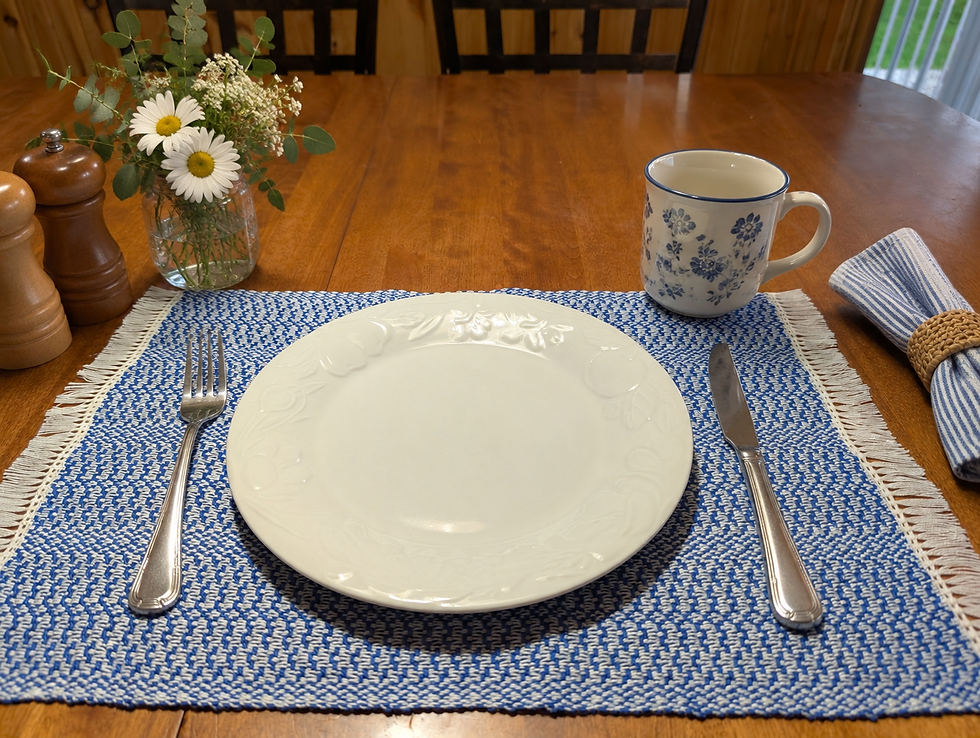 Royal blue and white handwoven placemat styled for everyday dining with white plate, cutlery, flowers and mug