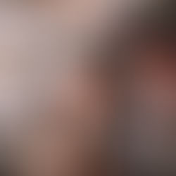 Couple souriant en manteaux d’hiver au marché de Noël, échangeant un moment tendre devant un sapin enneigé