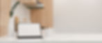An iPad rests on the white countertop of a beautiful, modern kitchen, next to a white vase and coffee mug.