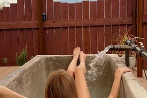 Woman soaking in a mineral water tub at a spa on Miracle Hill