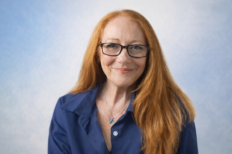 Smiling woman with long red hair and glasses.