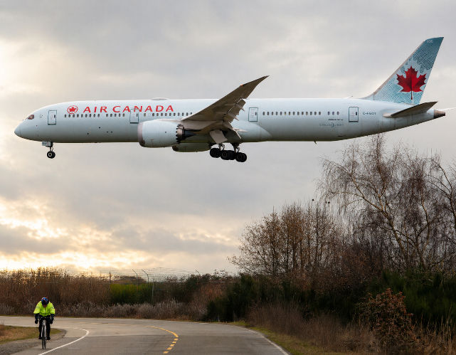Air Canada Jet arrives at YVR over bushes and manriding bike