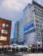 The Cobalt Hotel, a weathered building with a fire escape, stands against a striking sunrise sky in Vancouver. Soft hues of o