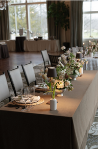 Elegant table setting with cream linens, arranged white flowers, wine glasses, and place cards on plates, creating a serene atmosphere.