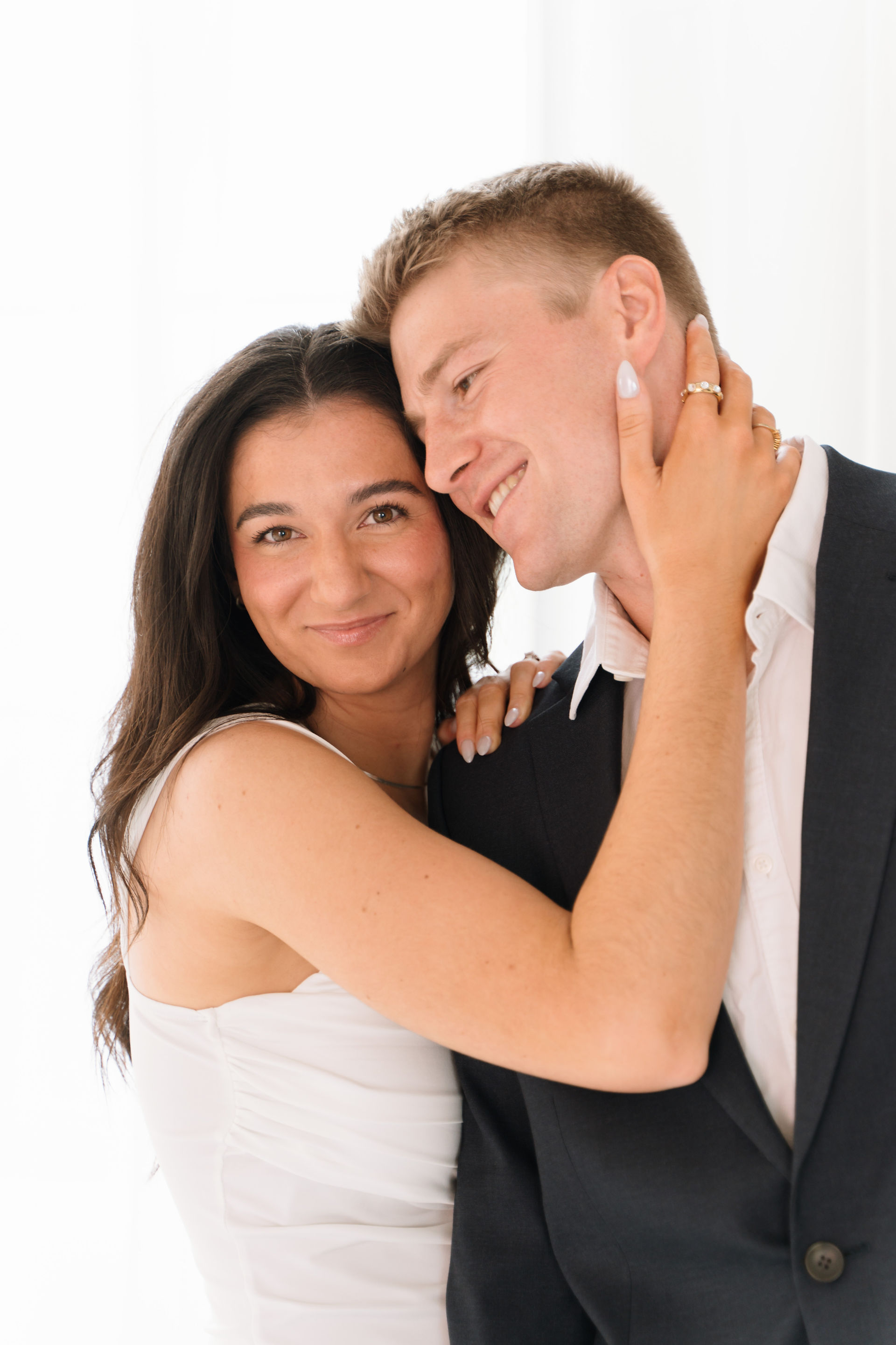 engaged couple pose in front of window