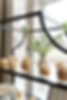 Cupcakes with frosting on a shelf, next to white flowers in a vase. Bright window background sets a cozy, inviting mood.
