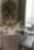 Elegant table setting with floral centerpiece, lit candles, and floral-patterned tablecloth. Large window in the background. Cozy mood.