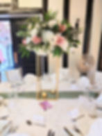White and dusky pink roses with green foliage on tall gold square stand