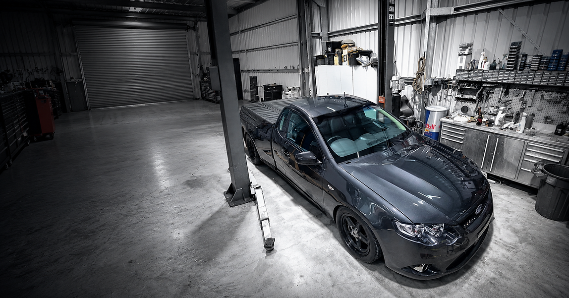 Black Ford Falcon ceramic coated inside Empire Refinish workshop showcasing deep gloss and mirror-like paint finish