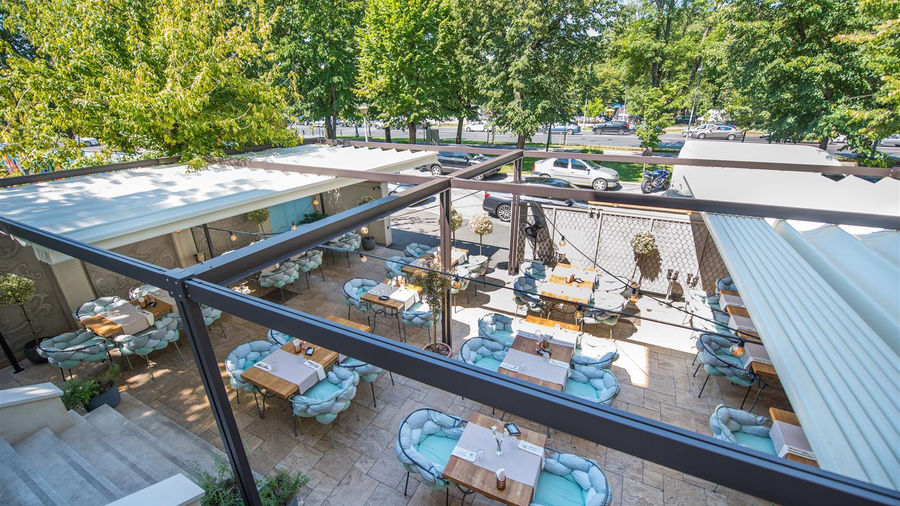 A large restaurant terrace with a retractable roof system with the roof open.