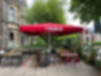 A jumbo umbrella on a restaurant terrace with a red canopy with a branded valance