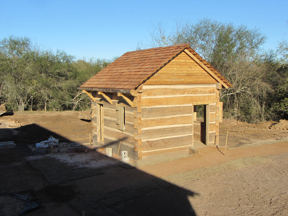 A small live edge oak log cabin with saddle notches.