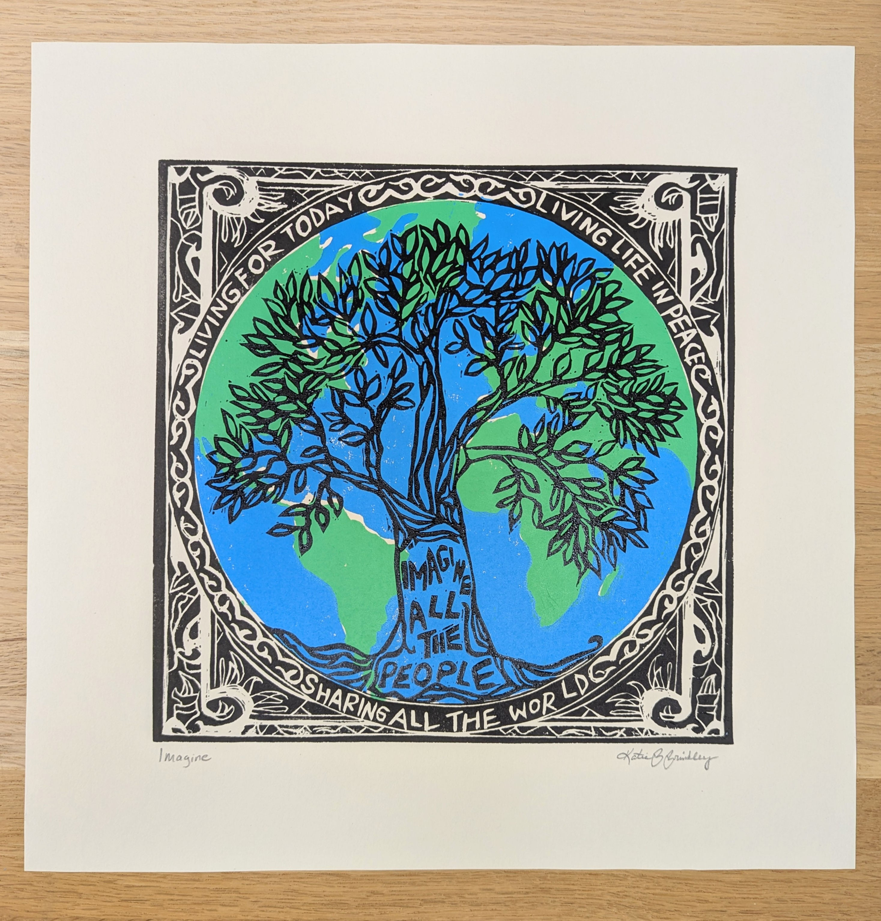 Linocut print with Imagine song lyrics, world in green and blue, with black tree and pattern