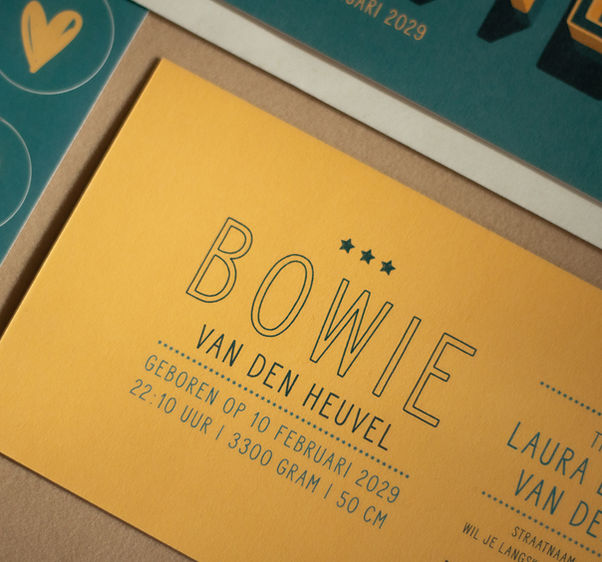 De okergele achterzijde van geboortekaartje Bowie met strakke turquoise typografie en drie kleine sterretjes.