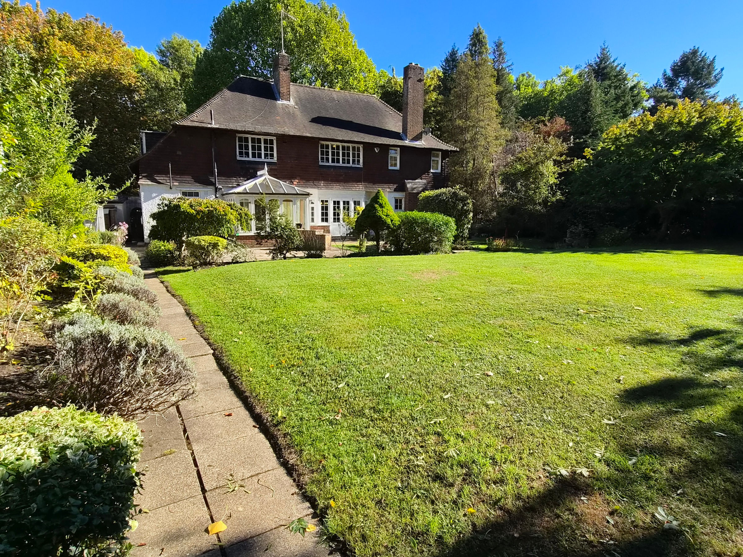 Detached period house with a large lawned garden in autumn sunshine, England