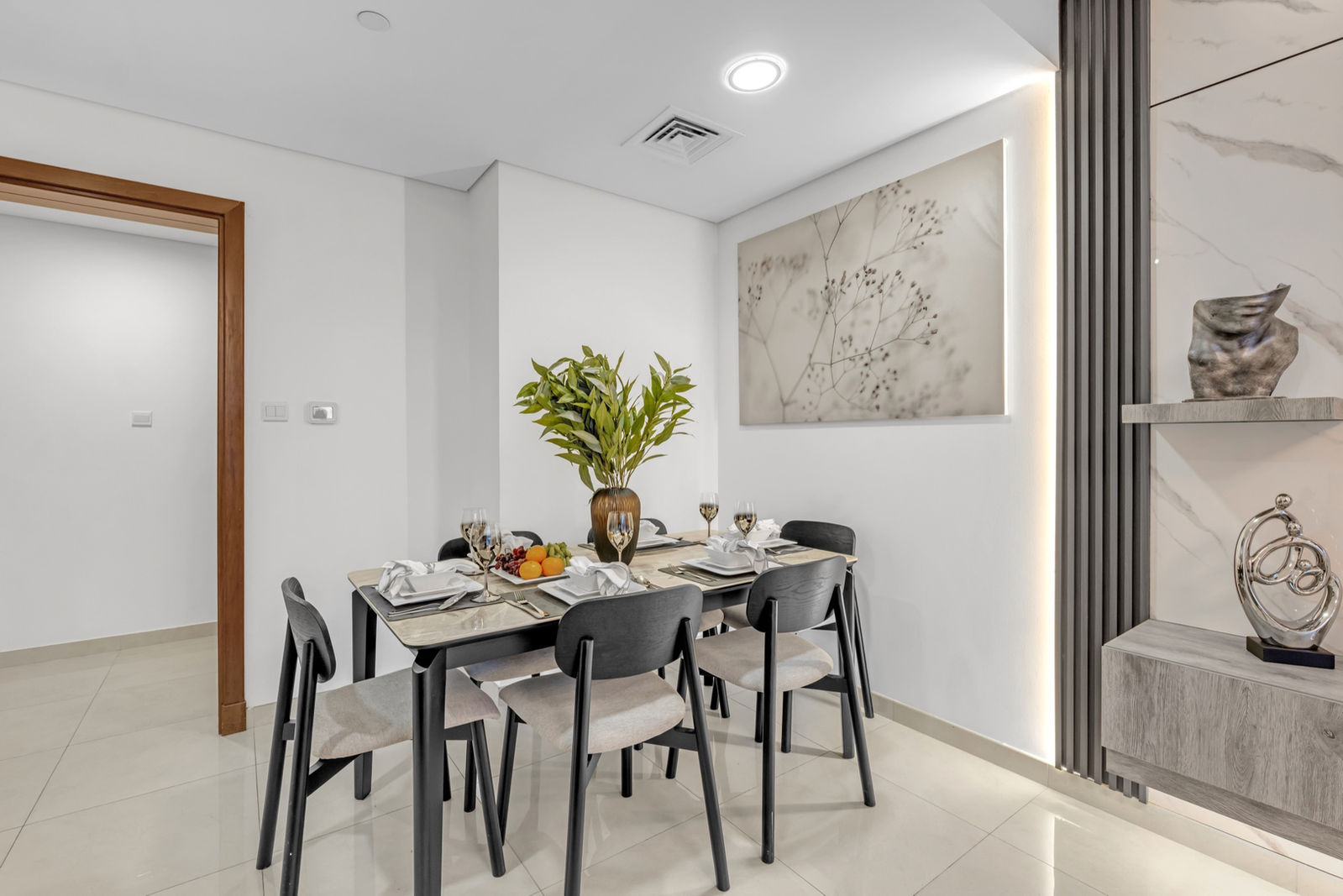 Dining table set for six beside a marble feature wall in a Waves Tower apartment, Dubai