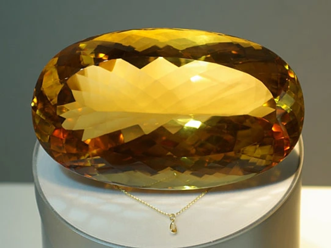 Worlds' Largest Faceted Citrine sitting on a length, showcased next to a small necklace showing the size difference.