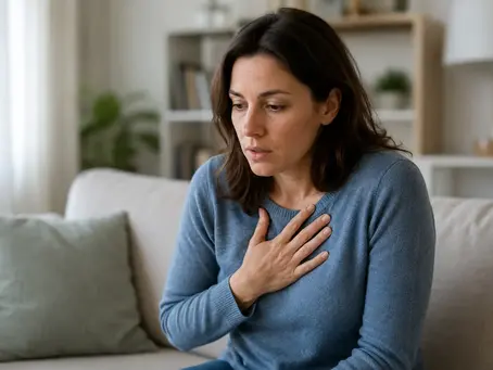 Femme inquiète, main sur la poitrine, ressentant des palpitations et une accélération du rythme cardiaque.