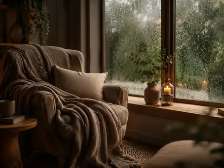 Fauteuil confortable près d’une fenêtre sous la pluie, illustrant un Safe Place ou refuge mental apaisant.