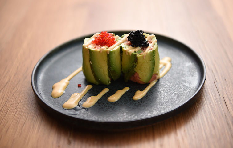 Sushi roll with caviar on a black plate, a delicious meal. Sushi Ginza